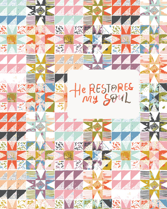 A square quilted fabric panel with a colorful geometric star and triangle pattern surrounding a central white square that reads 'He Restores My Soul' in mixed handwritten and printed lettering.