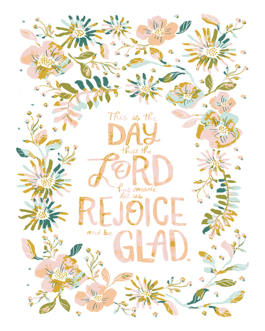 A square art print featuring a floral border in pastel pink, teal, and gold around a central typographic design that reads, 'This is the Day that the Lord made it glad to rejoice and be glad.' The background is white.